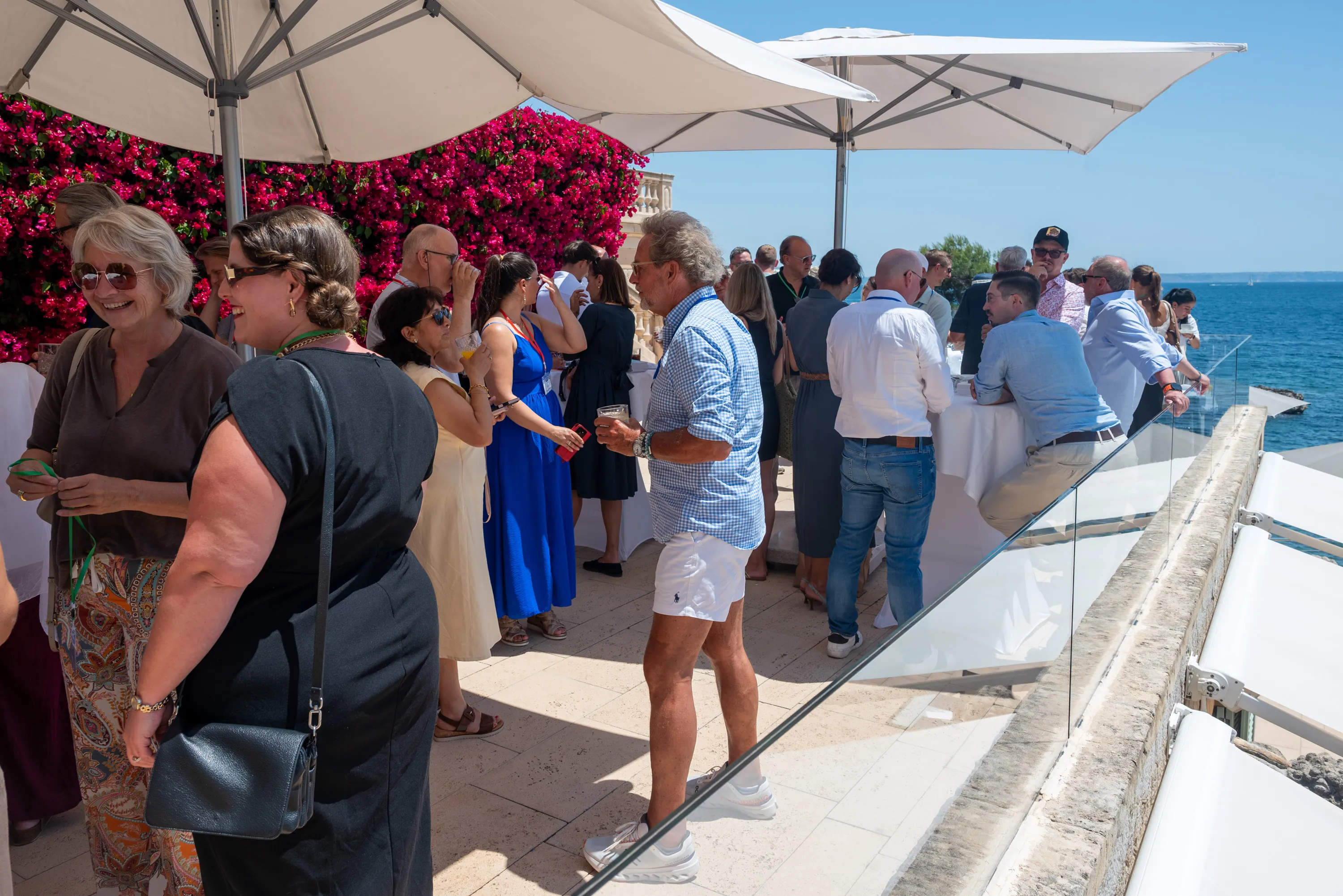 Empfang auf der Terrasse beim Palma Leadership Forum, Gäste im Gespräch unter Sonnenschirmen, dahinter das offene Meer